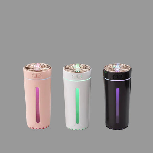 Three cylindrical humidifiers emitting mist on a wooden surface with a gray background
